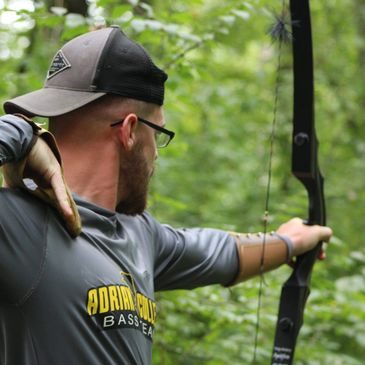 Traditional archer at full draw with a recurve in the woods